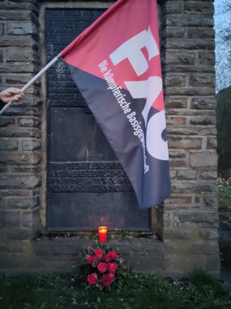 Friedrich Flender Stehle mit Gedenkkranz und -kerze und Fahne der FAU.